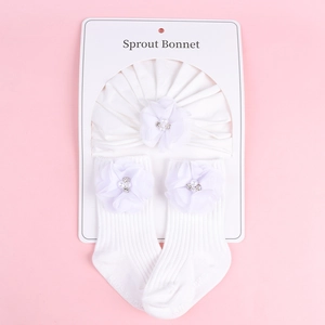 Détail de l'ensemble bonnet et chaussettes bébé blanc avec fleurs en tulle et perles