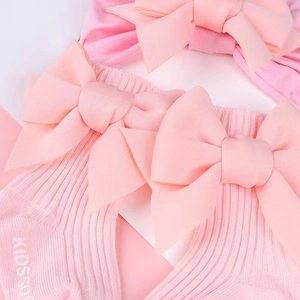 Dettaglio ravvicinato di calze per neonati rosa a coste con un grande fiocco decorativo