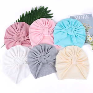 Detail view of six colorful soft knit infant turban hats with handmade knot design