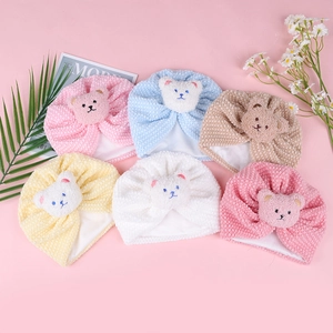 Detail showing colorful baby turbans with cute teddy bear patches and soft knit texture