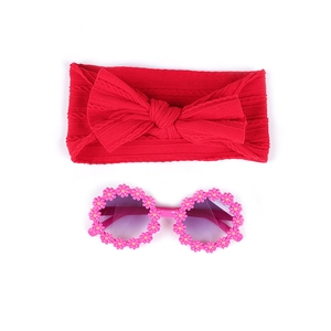Détail d'un bandeau en maille rouge à nœud et lunettes de soleil fleurs roses