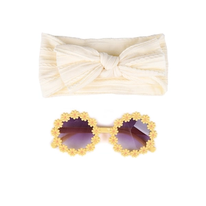Détails d'un bandeau pour bébé avec nœud tricoté et lunettes de soleil marguerites jaunes