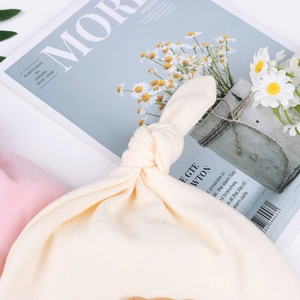 Detailansicht der beigen Baby-Knotenmütze aus weichem Baumwollstrick mit niedlichem Knoten