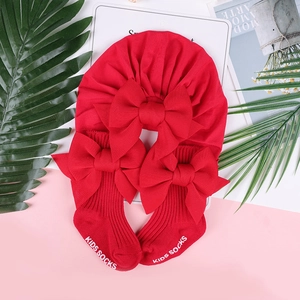 Dettaglio del set cappello turbante rosso e calzini per neonato con grandi fiocchi