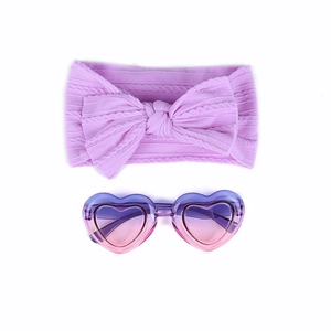 Détail d'un bandeau à nœud violet et lunettes de soleil en cœur pour bébé