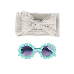 Détail d'un bandeau bébé beige avec lunettes de soleil fleuries vert menthe pour enfants