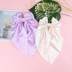 Détails macro de grandes barrettes nœuds en satin avec strass en violet et beige