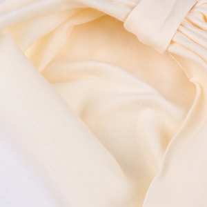 Detailed close-up of soft cream knitted baby hat fabric showing neat stitched seam and texture