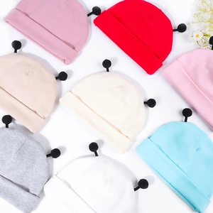 Détail de bonnets en tricot pour bébé en coton doux avec double pompons multicolores