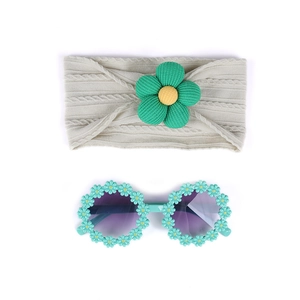 Détail du bandeau tricoté beige pour bébé avec fleur et lunettes de soleil marguerites