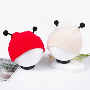 Vue détaillée de bonnets tricotés pour bébé rouge et beige avec antennes sur têtes