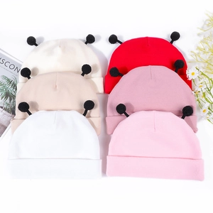 Mise à plat de six bonnets tricotés pour bébé avec pompons noirs mignons sur fond blanc