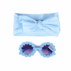 Détail d'un bandeau pour bébé avec nœud bleu et lunettes de soleil rondes avec marguerites