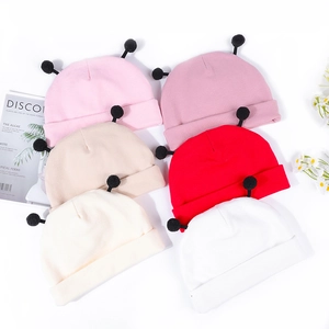 Mise à plat de bonnets en tricot pour bébé en six couleurs avec pompons noirs mignons