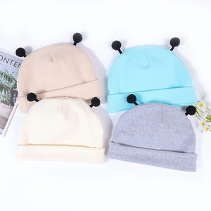 Mise à plat de bonnets tricotés pour bébé avec pompons en beige, bleu, blanc et gris