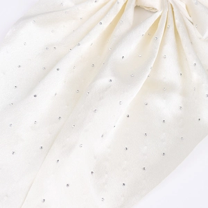 Détail du nœud en satin crème orné de strass scintillants sur la surface soyeuse