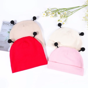 Mise à plat de bonnets tricotés pour bébé avec pompons en rouge, kaki, crème et rose