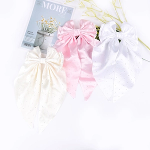 Détail de barrettes en satin avec strass dans les tons crème, rose et blanc