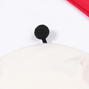 Détail rapproché d'un bonnet blanc pour bébé en coton doux avec un pompon noir pelucheux