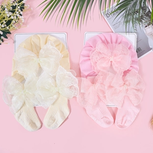 Detail von Baby Baumwollmützen und Socken mit großen Spitzenschleifen und Perlen in Rosa