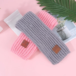 Detailed texture of knitted ribbed headbands with brown leather patches and logo