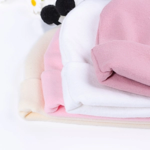 Détail de bonnets en maille côtelée pour bébé en crème, rose et blanc avec texture