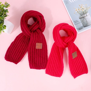 Close-up of thick rib-knit scarves in red and burgundy with brown leather brand labels