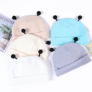 Vue à plat de bonnets en tricot pour bébé colorés avec pompons noirs et détails doux