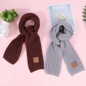 Close-up of knit texture and leather brand label on warm coffee and grey children scarves