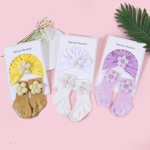 Detailaufnahme von Baby-Turban-Mützen aus Baumwolle und Socken mit Blumen in drei Farben