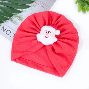 Detail of red knit baby Christmas hat with plush Santa Claus doll on white background