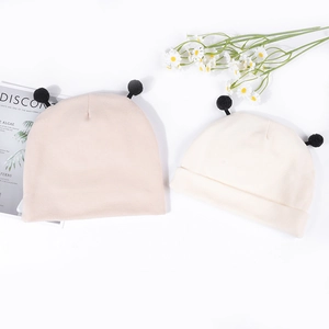 Détail de bonnets en tricot pour bébé en rose et beige avec pompons noirs mignons