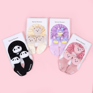 Flat lay of four pairs of cotton baby hats and socks sets with 3D plush animal dolls