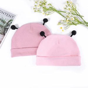 Gros plan de bonnets en tricot rose pour bébé avec pompons noirs et texture douce