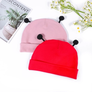 Détail de bonnets tricotés pour bébé rose et rouge avec pompons doux et bord replié