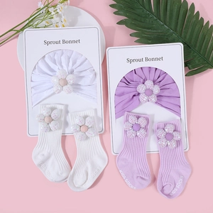 Detail von Baby-Baumwollhaube und Socken-Set mit Paillettenblumen auf rosa Grund