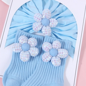 Detail von hellblauem Baby-Stirnband und Socken mit karierten Pailletten-Blumen