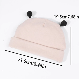 Bonnet tricoté rose pour bébé avec pompons noirs et dimensions de 21,5cm par 19,5cm