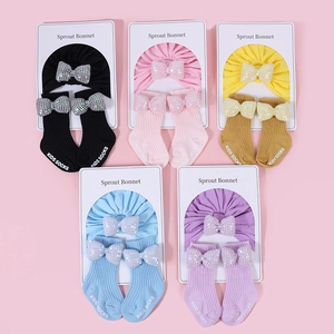 Dettaglio di set regalo neonato con fasce a fiocco di paillettes e calze a righe