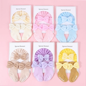 Detail showing various colors of cotton baby bonnets and matching bow socks sets