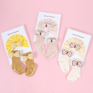 Detalle de conjunto de gorro y calcetines para bebé con lazos sobre tarjetas de cartón