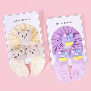 Detail of baby cotton bonnet and matching socks with cute bear and monster 3D designs