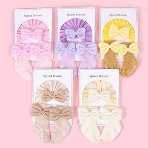 Detailed set of cotton baby bonnets and socks with large bows in five soft pastel colors