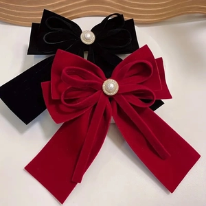 Close-up of velvet bow hair clips with pearl center and golden bead trimming