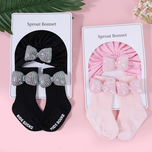 Dettaglio di turbanti per neonati e calze con fiocchi di paillettes in nero e rosa