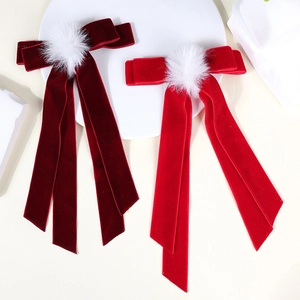 Detail of red velvet bow hair clips with white pom-poms for festive holiday styling