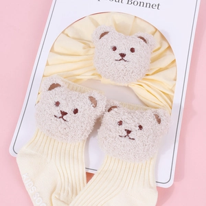 Detailed close-up of baby yellow headband and bear socks set for infant girls
