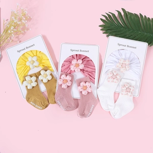 Détail à plat de bonnets en coton pour nouveau-né et chaussettes assorties avec fleurs 3D