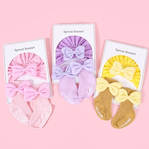 Detail of baby cotton bonnet and socks set with elegant bows and ribbed texture