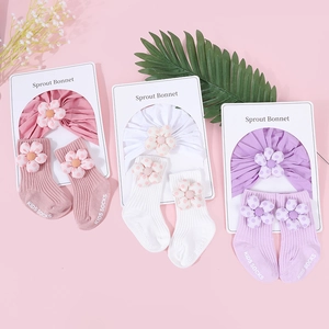 Détail du coffret de trois bonnets et chaussettes en coton pour nouveau-né avec fleurs